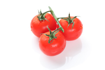 Three cherry tomatoes on green branch