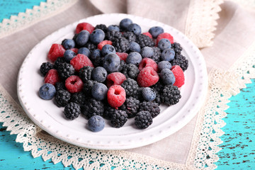 Iced berries on plate, on color wooden background