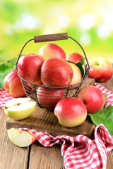 Naklejka na ściany i meble Sweet apples in wicker basket on table on bright background