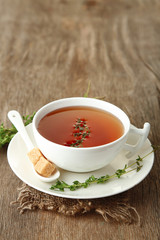 Cup of tasty herbal tea with thyme on wooden table