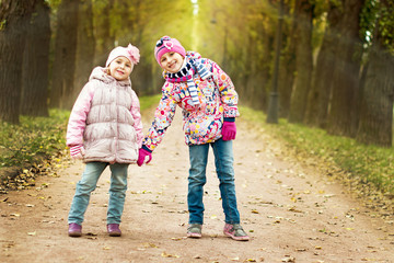 two girls playing in the park in autumn