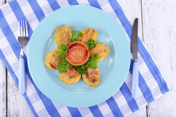 Baked potato with bacon on plate, on wooden background