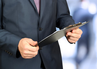 Business man in a formal suit  holding documents in his hands