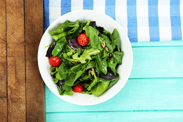 Fresh green salad in bowl on wooden table
