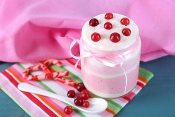 Raspberry milk dessert in glass jar, on color wooden background