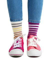 Female legs in colorful socks and sneakers isolated on white