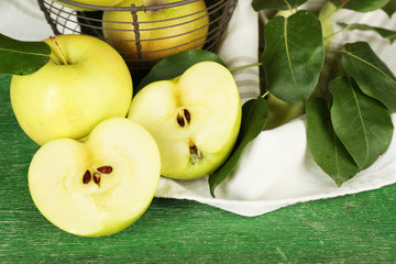 Ripe apples in metal basket with napkin on wooden background