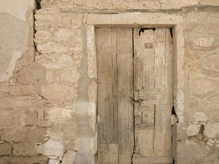 Bröckelndes Mauerwerk aus Naturstein und alte Holztür in Khaki un d Naturfarben in den Gassen der...