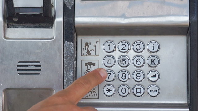 Close-up of a man's hand taking an outdoor payphone