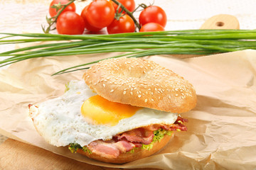 Sandwich with fried bacon and egg on a chopping board