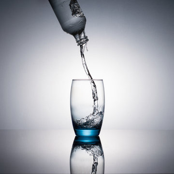 Water flowing and splashing from a glass bottle