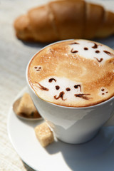Cup of coffee with cute drawing on table, close up