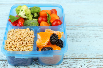 Tasty vegetarian food in plastic box on wooden table