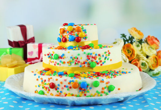 Beautiful tasty birthday cake and gifts on light background