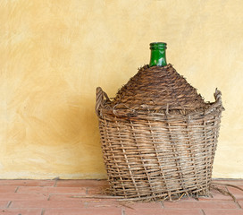 Old demijohn aka carboy for wine, wicker straw wrap, by house.
