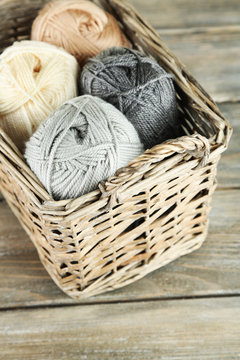 Knitting yarn in basket, on wooden background