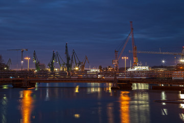 Fototapeta na wymiar Big cranes and bridge at the shipyard at night.