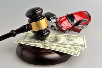 Hammer of judge with money and toy cars on gray
