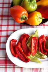 Pepper on oval and round plate on fabric background