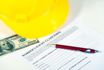 Worker injury claim hard hat with money and pen on white