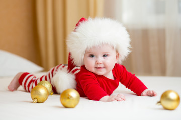 funny Santa baby girl lying on white bed © Oksana Kuzmina