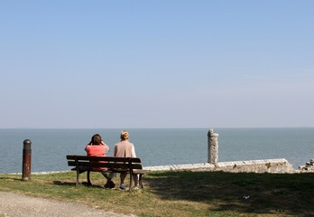 couple assis sur un banc et regardant la mer