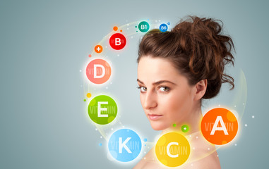 Pretty young girl with colorful vitamin icons and symbols