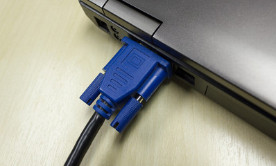VGA cable connected to laptop on wooden table