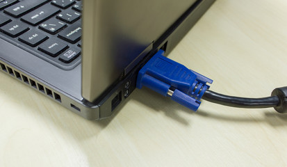 VGA cable connected to laptop on wooden table