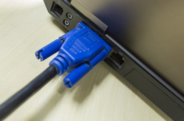 VGA cable connected to laptop on wooden table