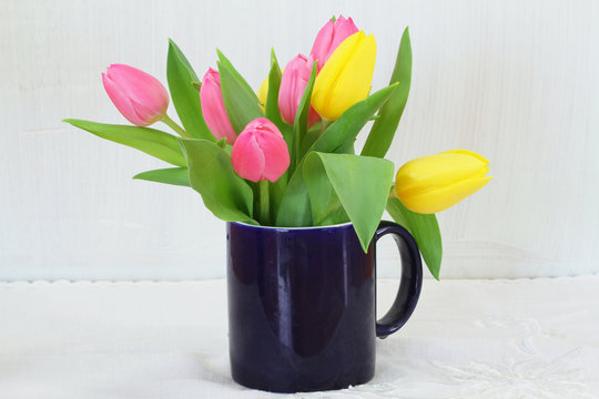 Fototapeta Pink and yellow tulips in navy blue mug