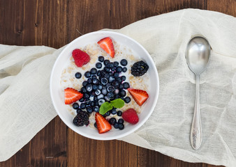 A bawl of oat porridge with fresh berries, honey, almond petals