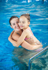 mother hugging daughter in swimming pool