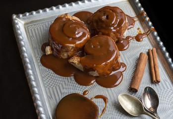 Cinnamon rolls with warm caramel topping and cinnamon sticks on