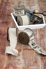 Old spools of thread, fabric, scissors on a wooden background
