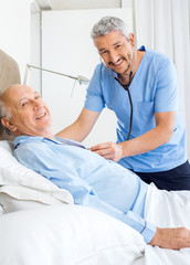 Obraz premium Portrait Of Happy Caretaker Examining Senior Man