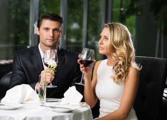 Cheerful couple in a restaurant with glasses of red wine