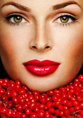 beautiful woman's face surrounded by red berries