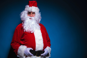 Santa looking at the camera while holding his belt.