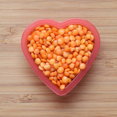 Red lentils heap in a heart bowl