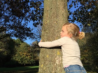 Mädchen umarmt einen Baum