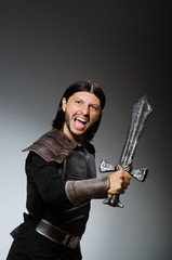 Fototapeta premium Angry knight with sword against dark background