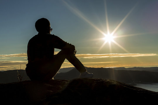 Silhouette man on a mountain enjoying the view at sunset