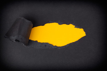 Yellow paper background appearing behind torn black paper