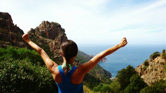 Young woman with arms outstretched looking to a sea