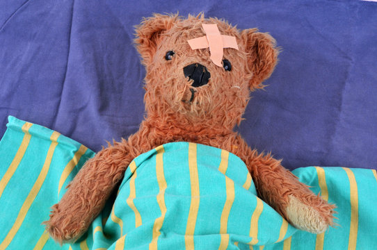 Ours en peluche bless&eacute; dans son lit