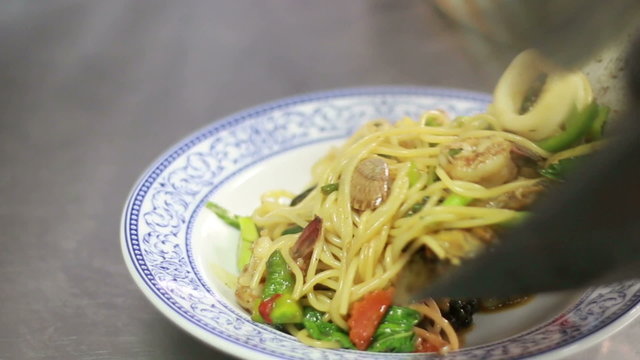 Chef preparing spicy seafood spaghetti on dish