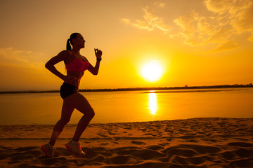 Woman running alone at beautiful sunset in the beach
