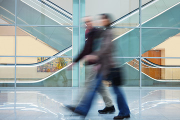 Two People Walking Quickly down Hall in Office Building