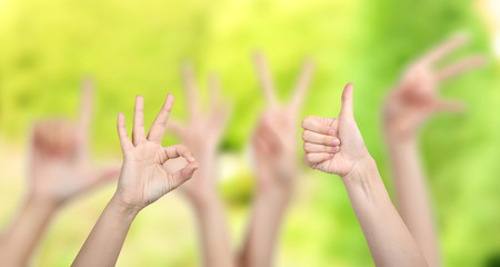 People show different hands signs on green background